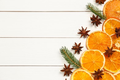 Photo of Flat lay composition with dry orange slices, fir branches and anise stars on white wooden table. Space for text