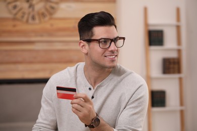 Photo of Man holding credit card for online payment at home