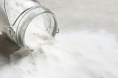 Photo of Overturned jar with baking soda on grey background. Space for text