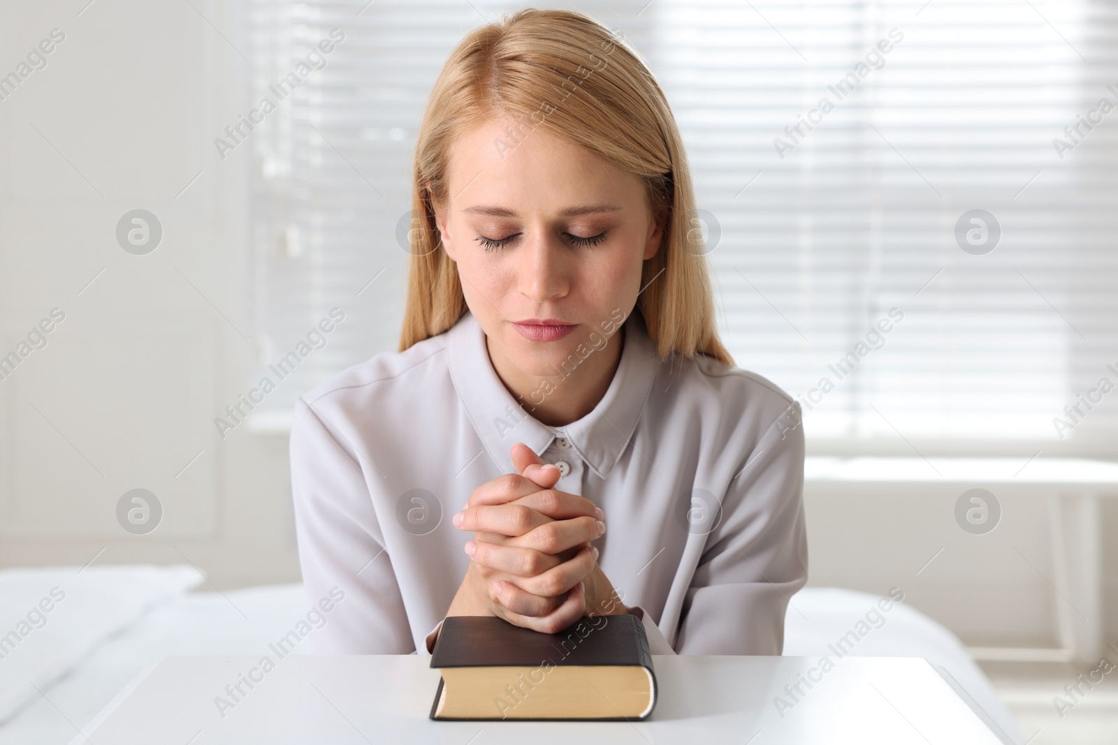 Photo of Religious young woman with Bible praying at home