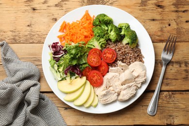 Balanced diet and healthy foods. Plate with different delicious products on wooden table, top view