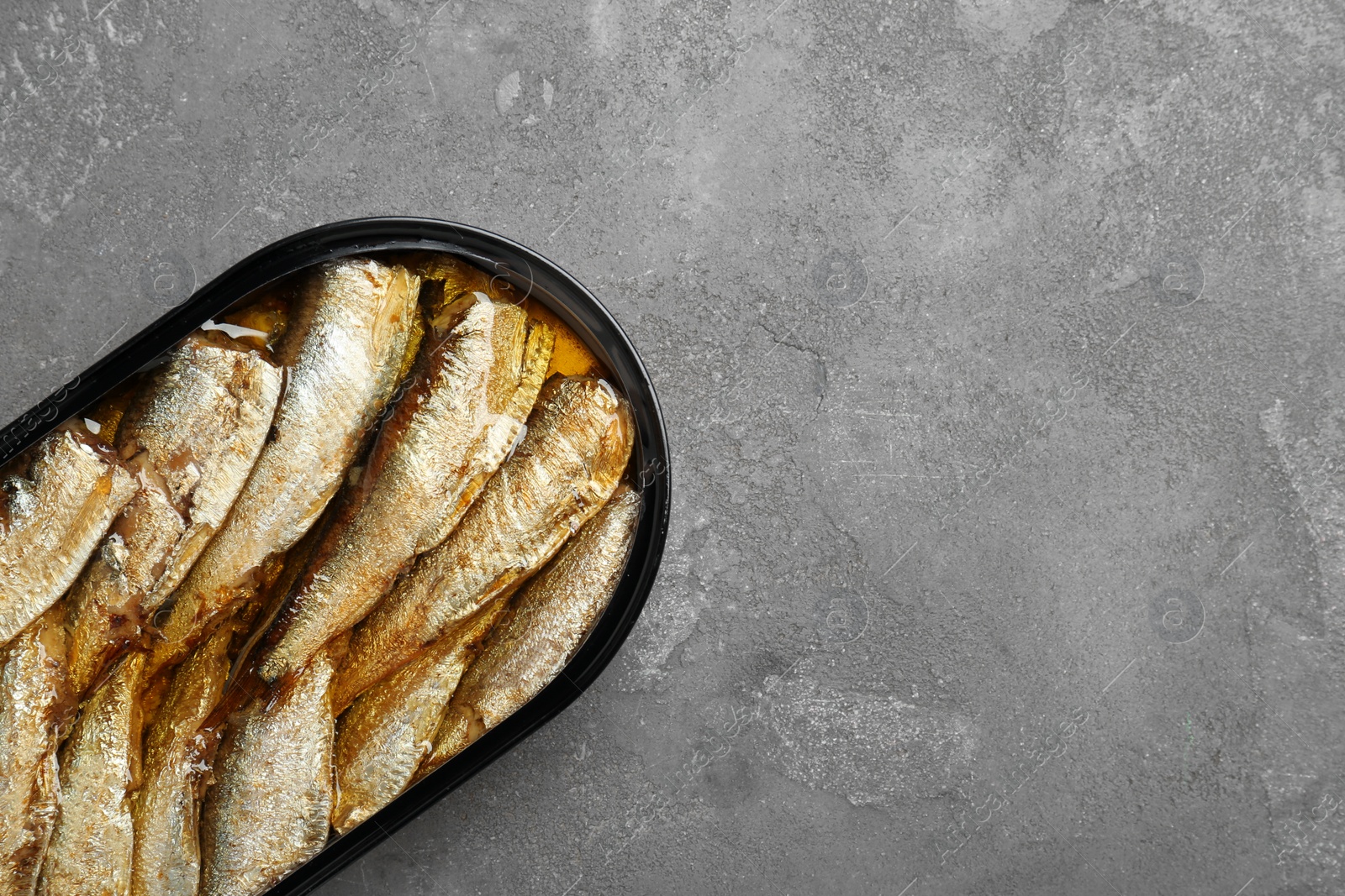 Photo of Canned sprats on grey textured table, top view. Space for text