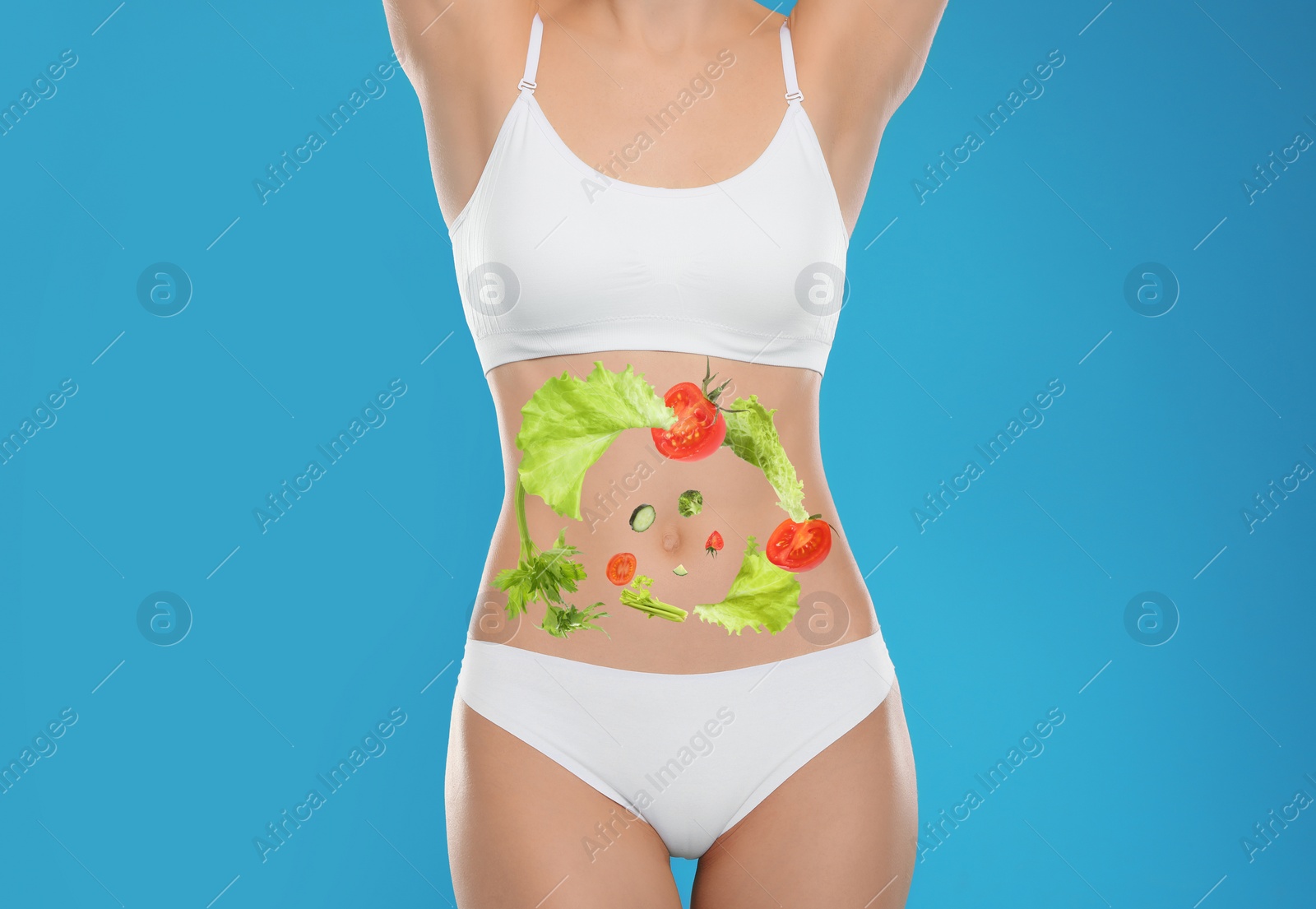 Image of Slim young woman and images of vegetables on her belly against light blue background. Healthy eating