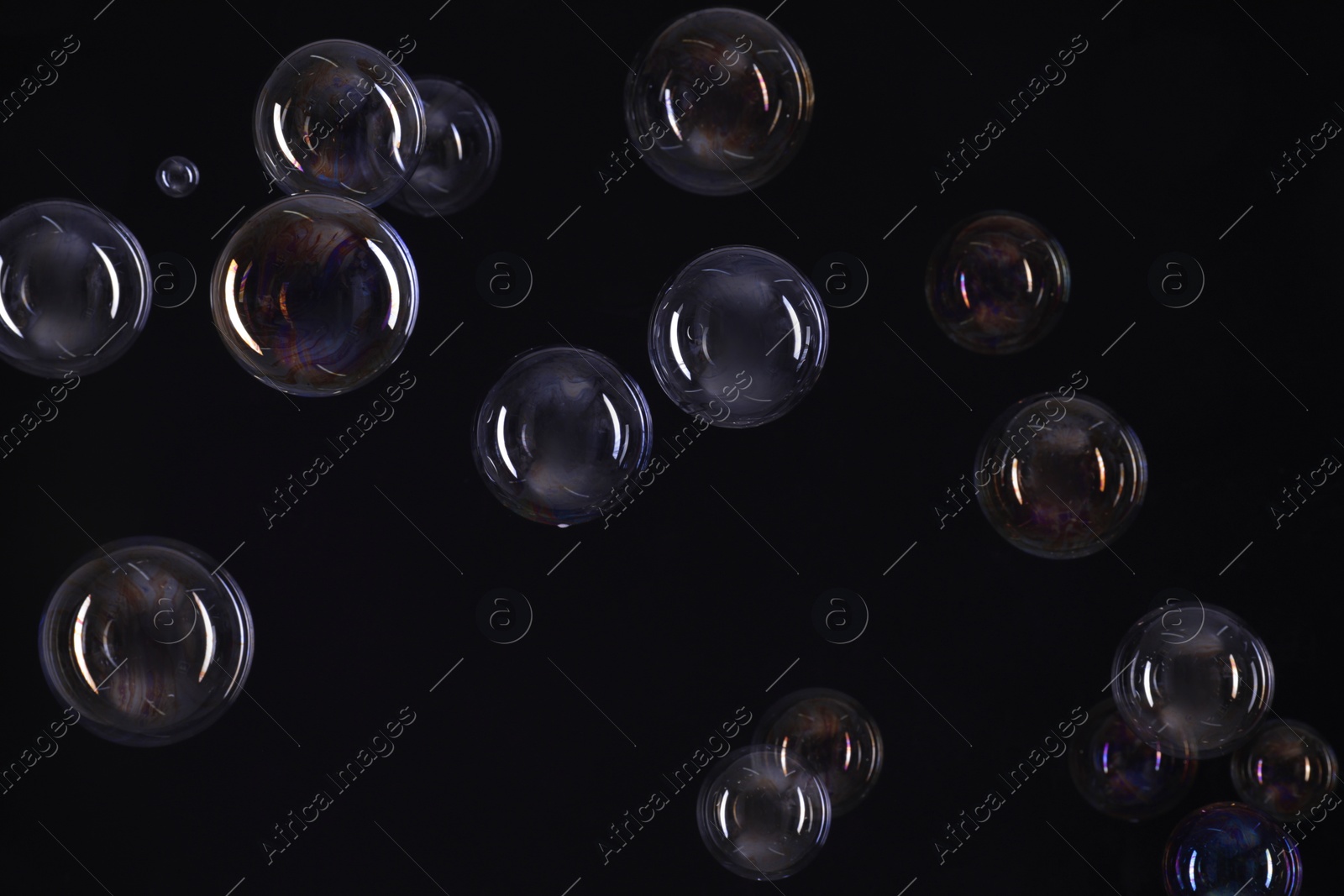 Photo of Many beautiful soap bubbles on black background