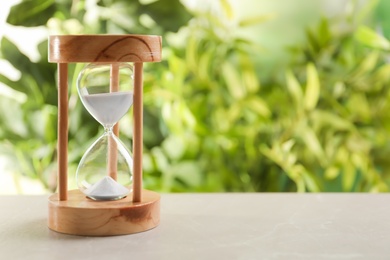 Hourglass with flowing sand on table against blurred background. Time management