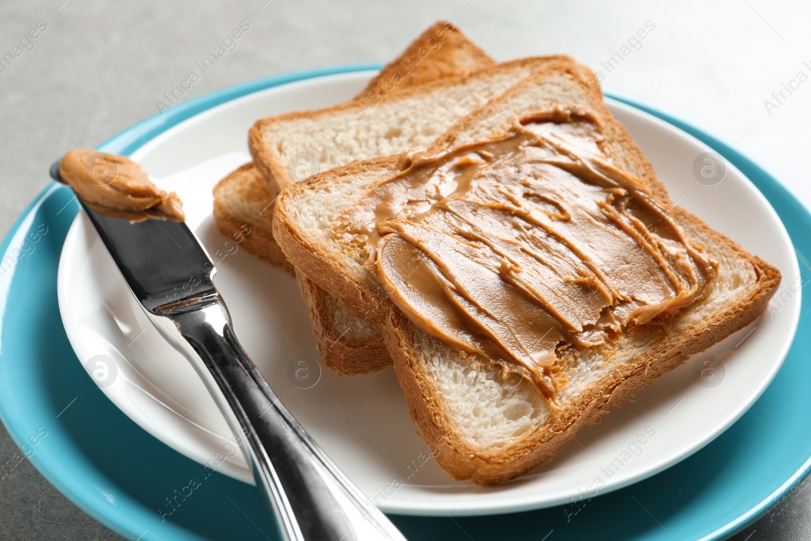 Photo of Plate with toast bread and peanut butter on table