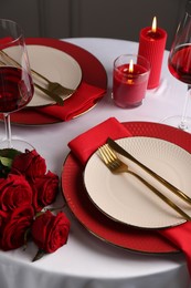 Photo of Place setting with roses and candles on white table. Romantic dinner