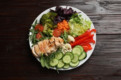 Balanced diet and healthy foods. Plate with different delicious products on wooden table, top view