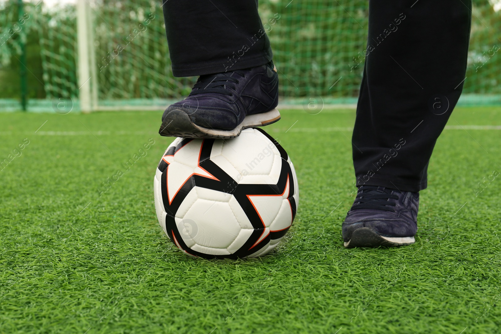 Photo of Man with soccer ball on green grass at stadium, closeup