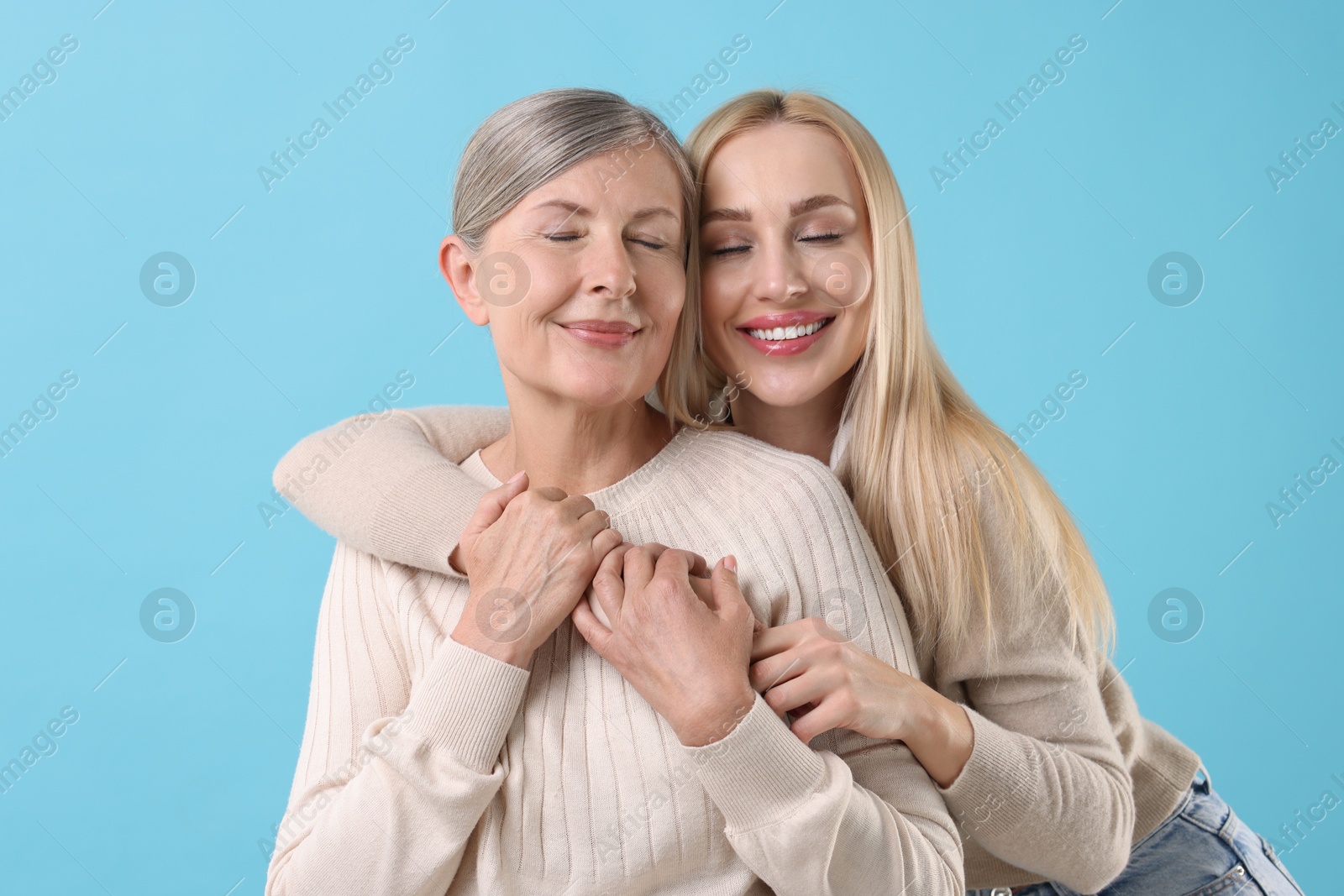 Photo of Family portrait of young woman and her mother on light blue background