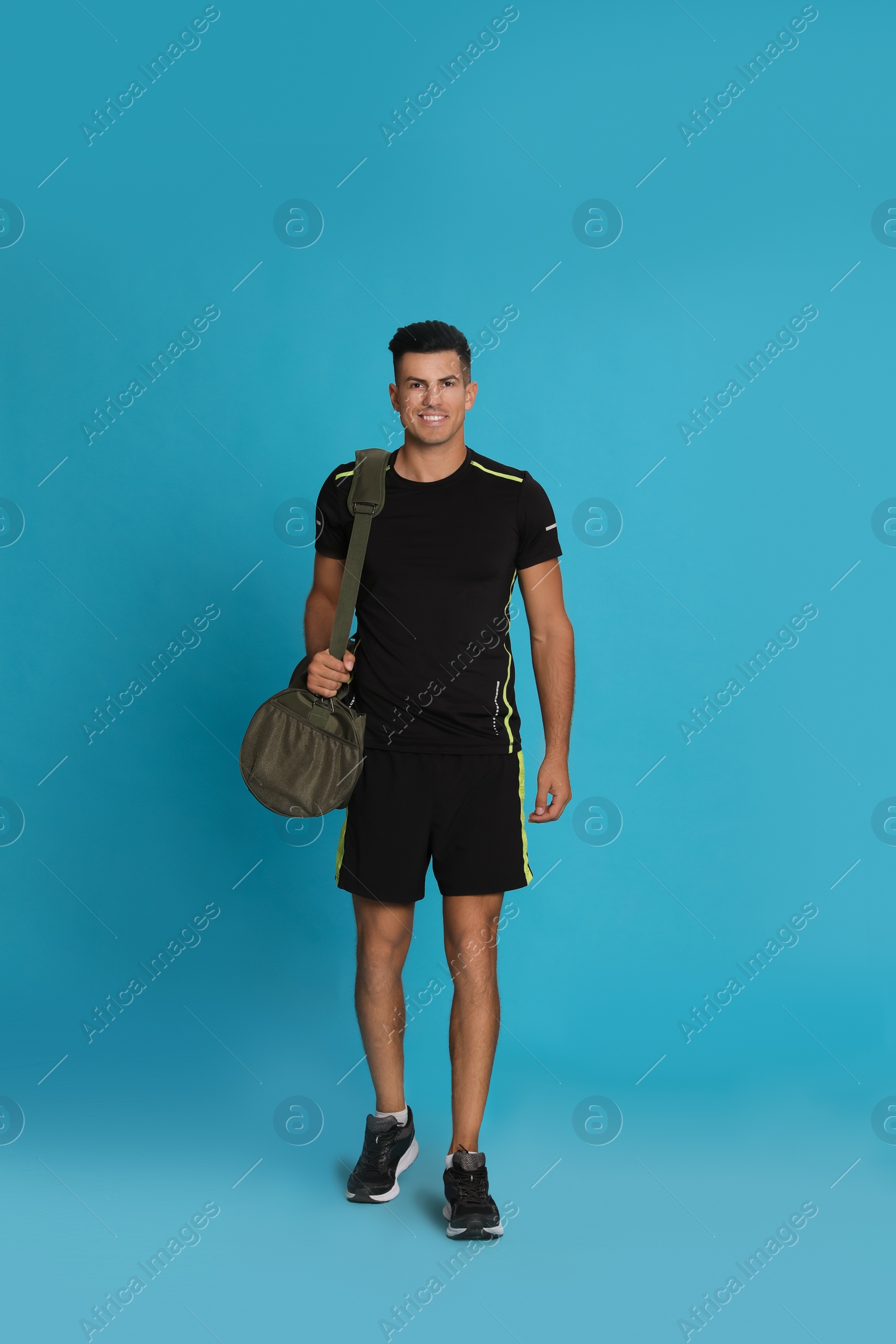 Photo of Handsome man with sports bag on light blue background