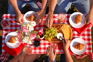 Photo of Group of people having picnic at table outdoors, top view