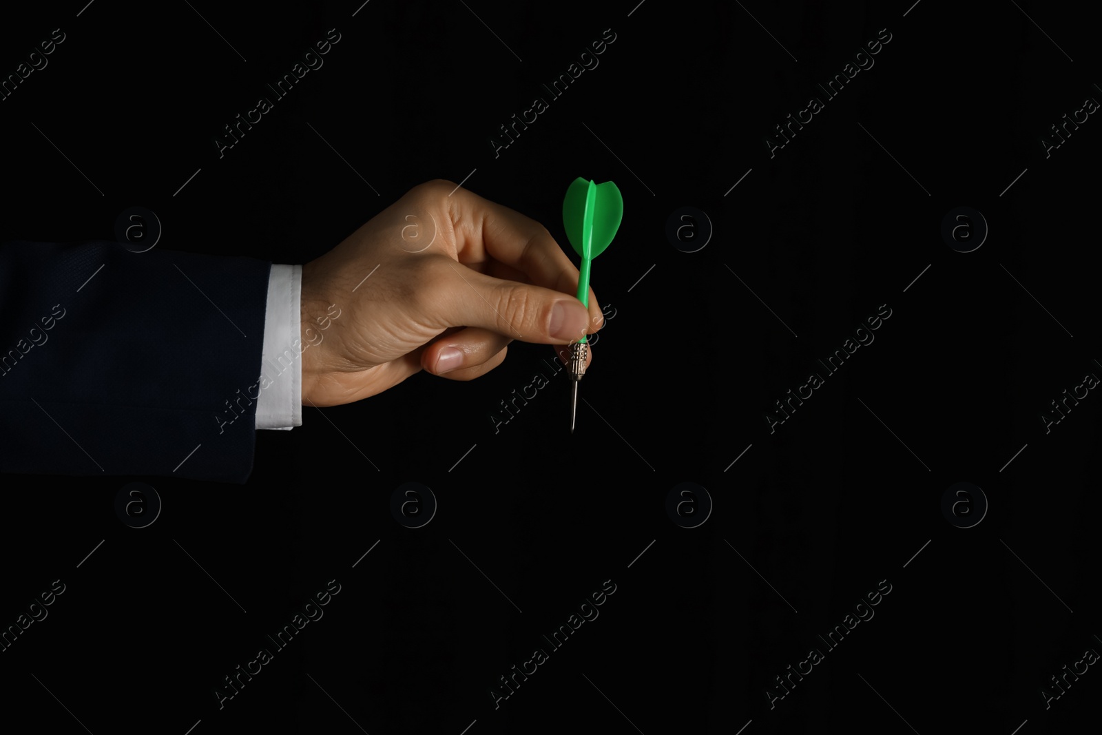 Photo of Man holding green dart on black background, closeup