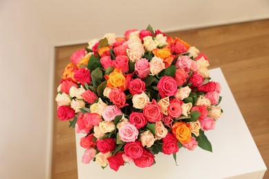 Bouquet of beautiful roses on white table indoors, top view