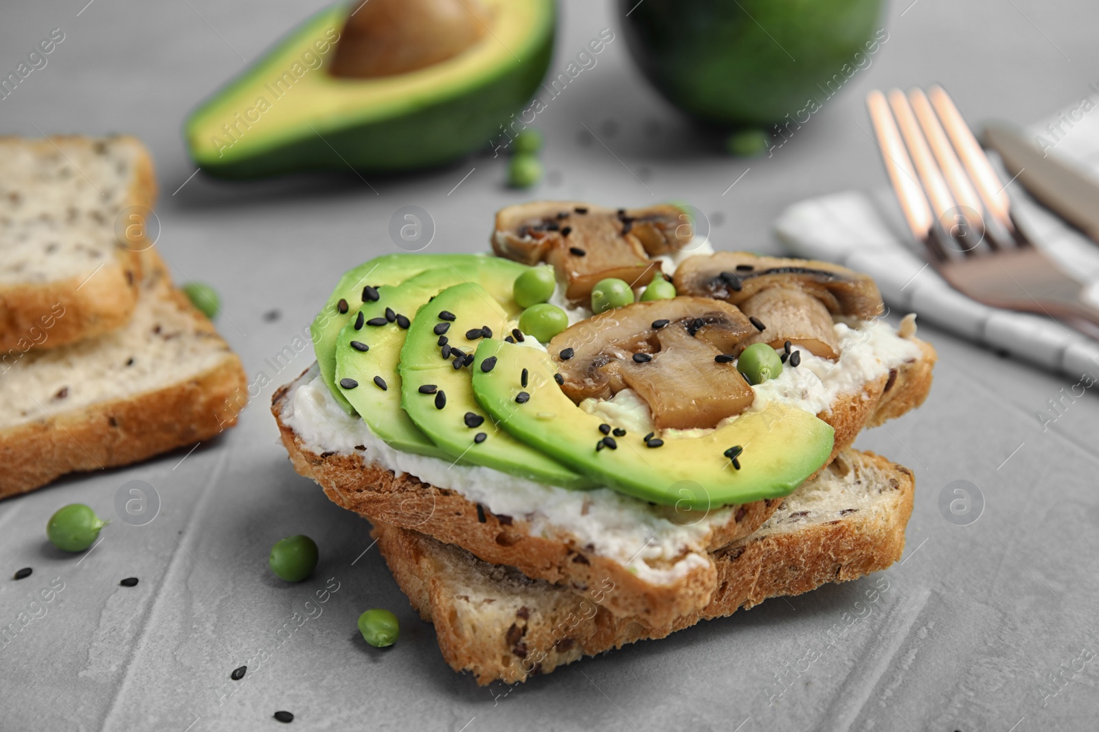 Photo of Crisp toast with sliced avocado, cream cheese and mushroom on table, closeup