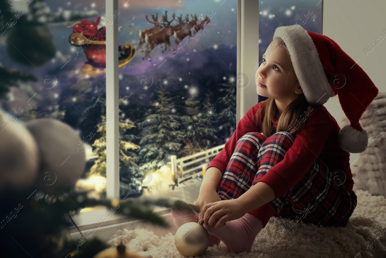 Image of Cute little girl on window sill at home waiting for Santa Claus. Christmas celebration