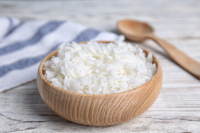 Photo of Bowl with tasty cooked rice on white wooden table, closeup