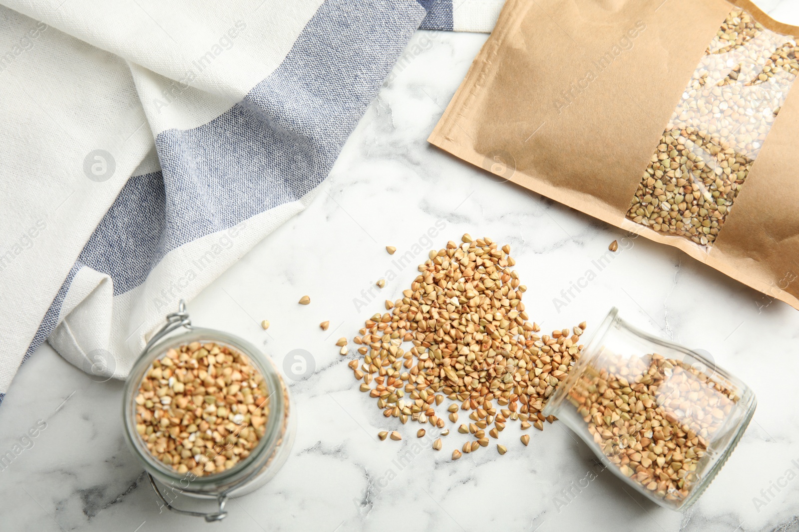 Photo of Uncooked green buckwheat grains on white marble table, flat lay