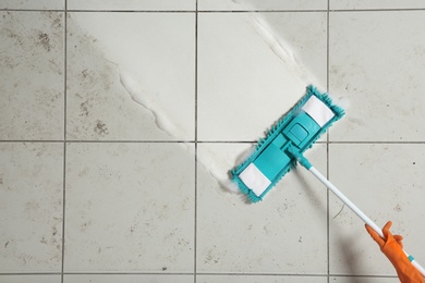 Professional cleaner washing dirty floor with mop, top view. Space for text