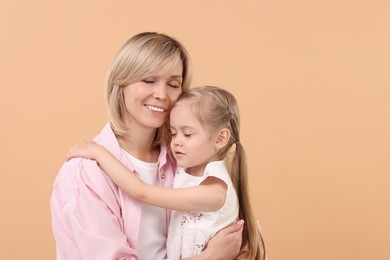 Photo of Family portrait of happy mother and daughter on beige background. Space for text