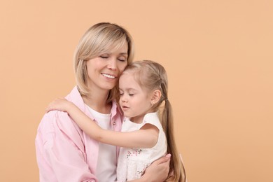 Family portrait of happy mother and daughter on beige background. Space for text