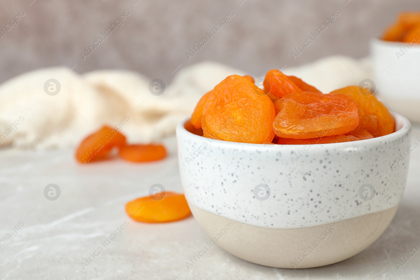 Photo of Bowl with apricots on grey table, space for text. Dried fruit as healthy food
