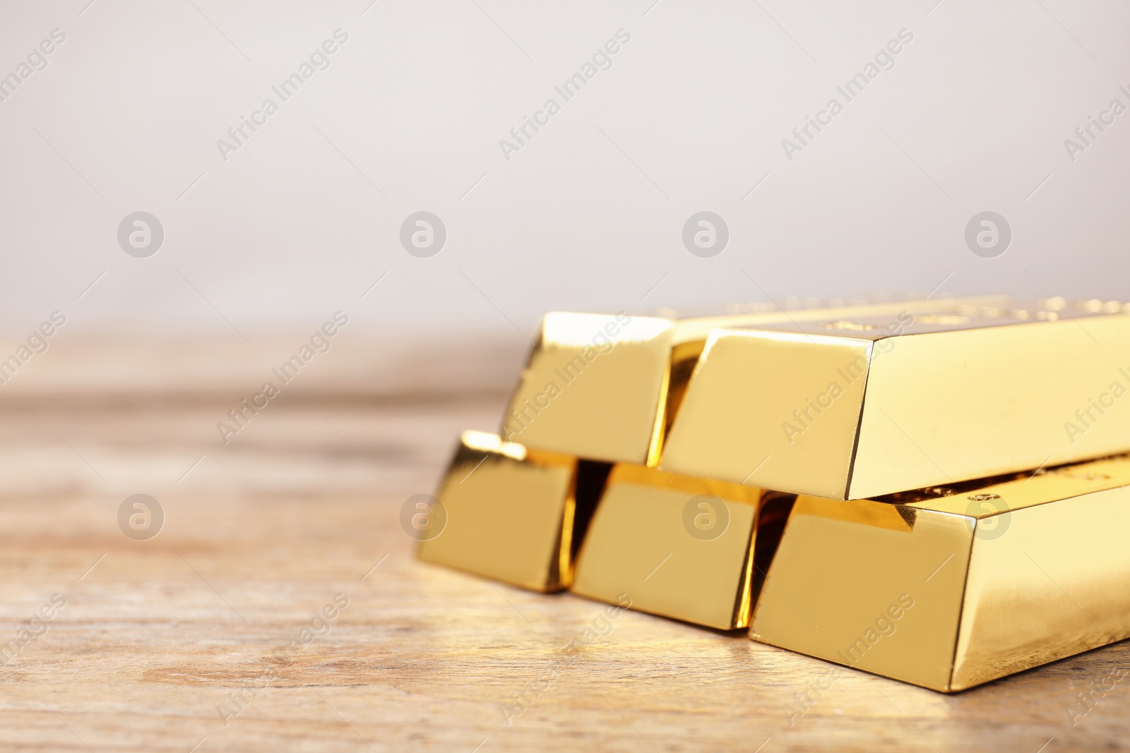 Photo of Shiny gold bars on wooden table. Space for text