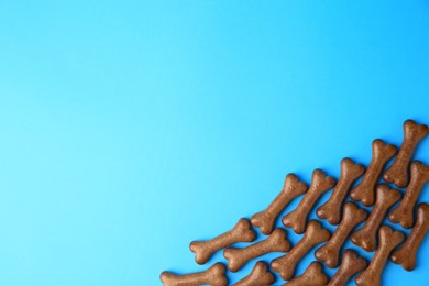 Bone shaped dog biscuits on light blue background, flat lay. Space for text