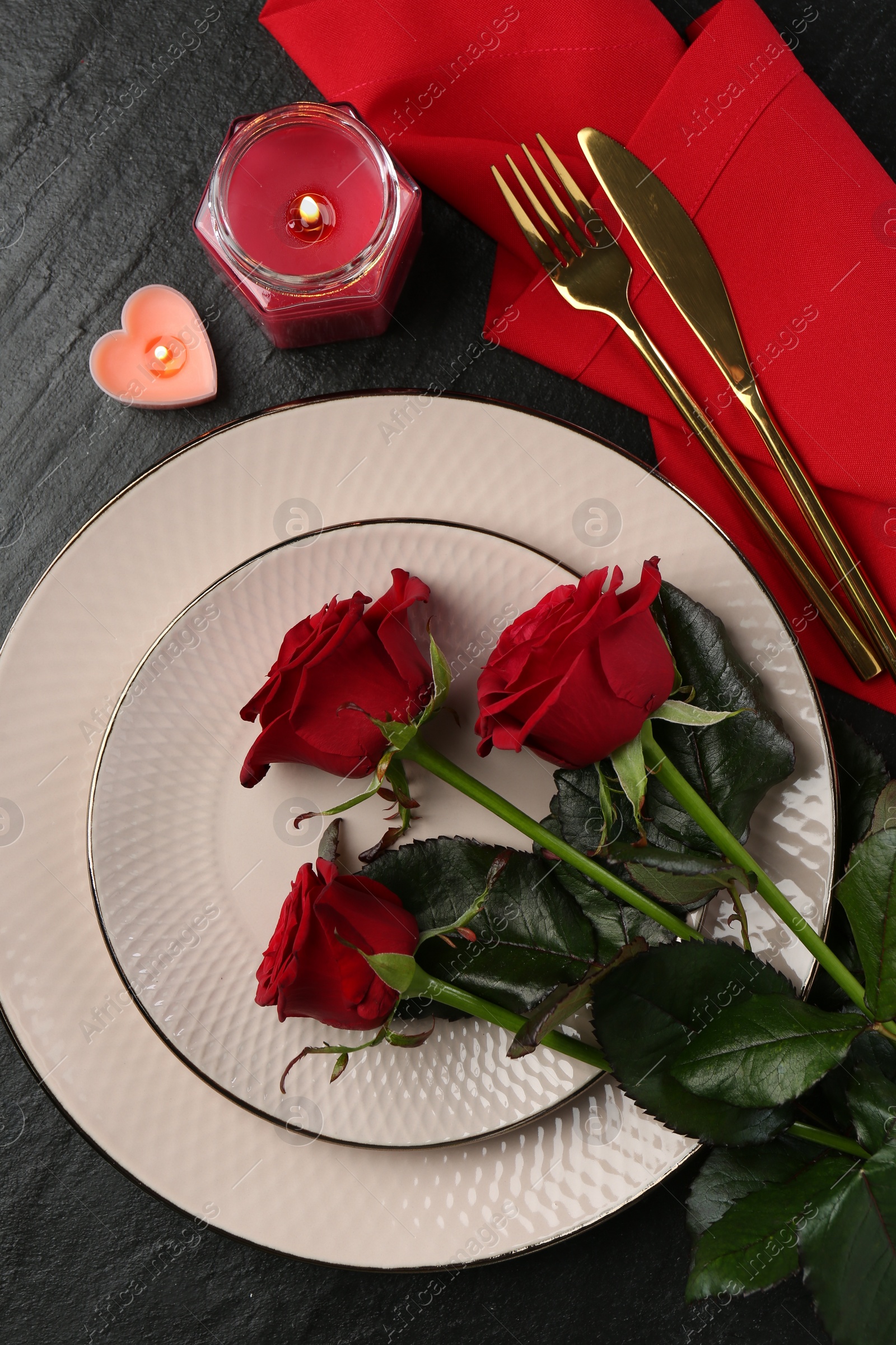 Photo of Place setting with candles and roses on grey textured table, flat lay. Romantic dinner