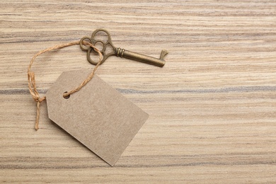 Photo of Vintage key with blank tag on wooden table, top view and space for text. Keyword concept