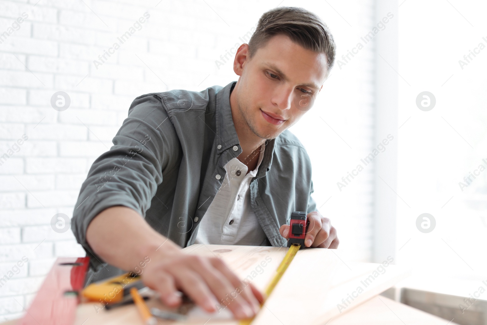 Photo of Young man working with measuring tape indoors