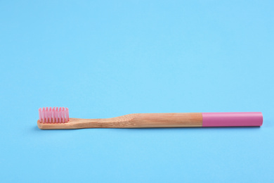 Photo of Toothbrush made of bamboo on light blue background