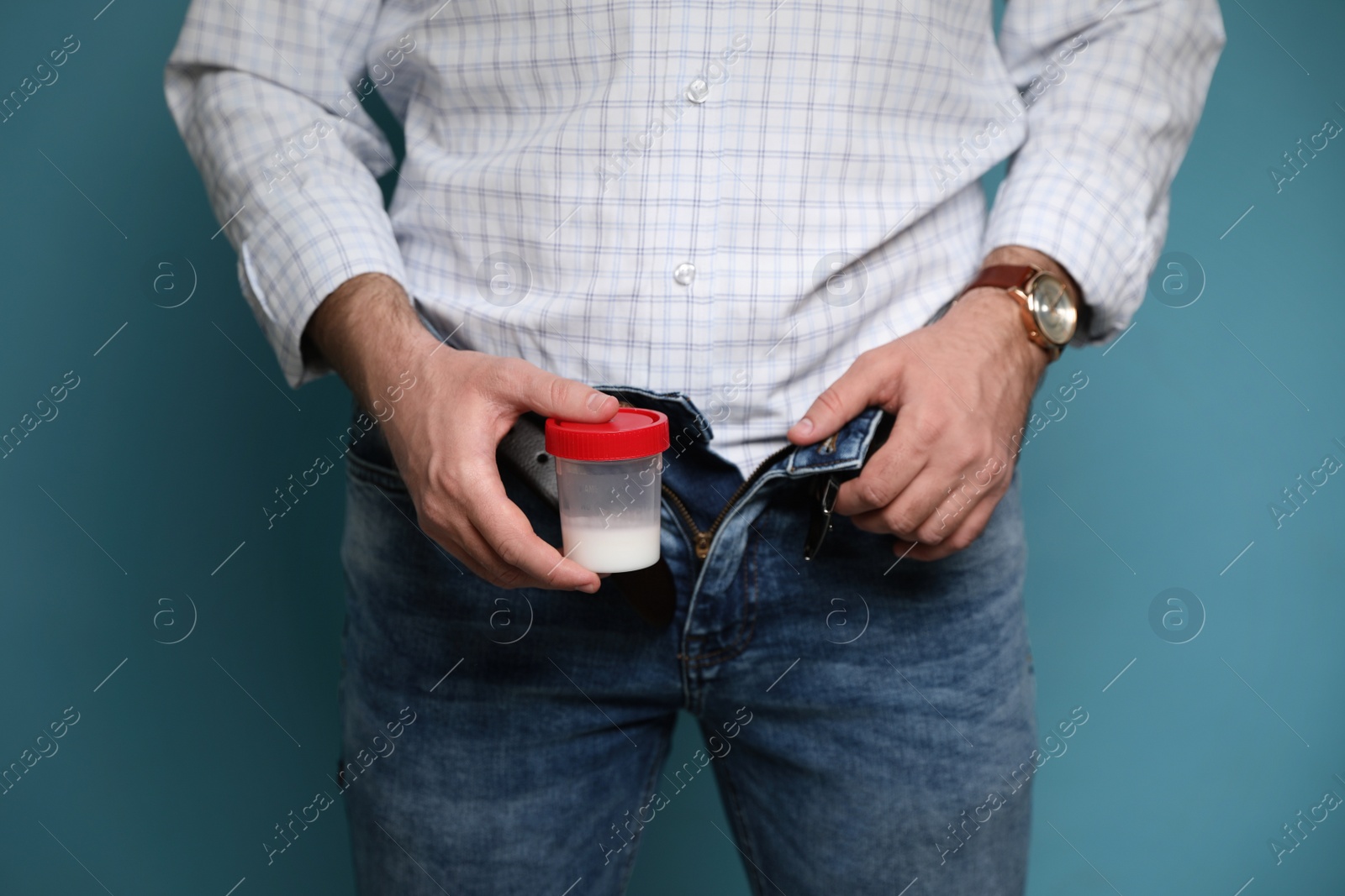 Photo of Donor with unzipped pants holding container of sperm on turquoise background, closeup