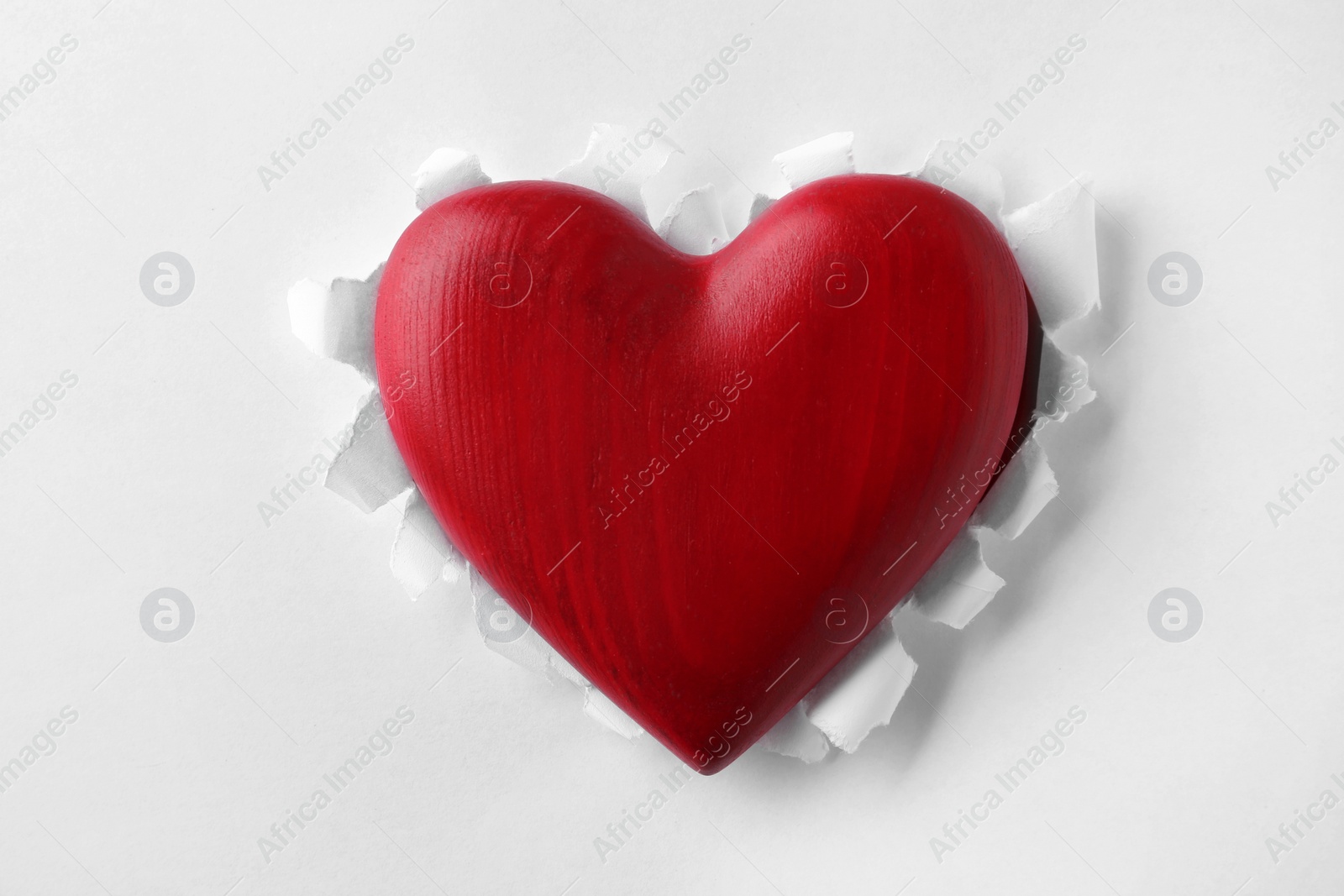 Photo of Red wooden heart on white paper, top view