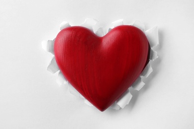 Photo of Red wooden heart on white paper, top view