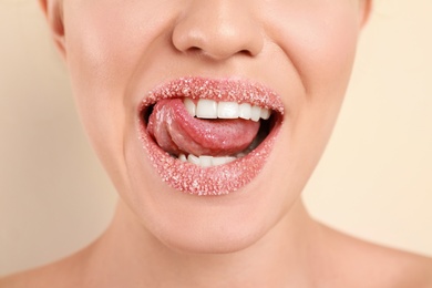 Photo of Young woman with sugar lips on beige background, closeup