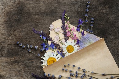 Photo of Flat lay composition with beautiful dried flowers in envelope on wooden background