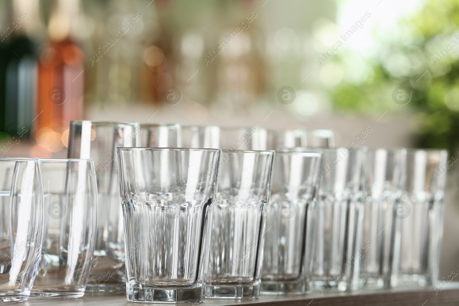 Photo of Empty glasses on wooden table against blurred background