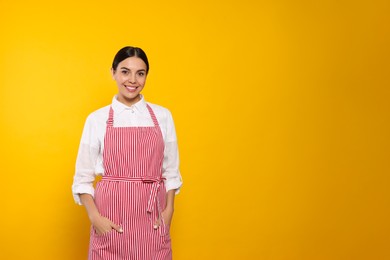 Photo of Young woman in red striped apron on yellow background, space for text