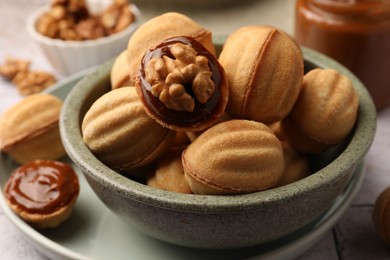 Photo of Delicious nut shaped cookies with boiled condensed milk in bowl, closeup