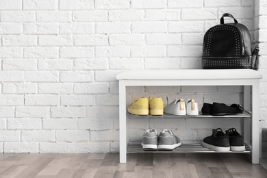 Photo of Collection of stylish shoes on rack storage near white brick wall