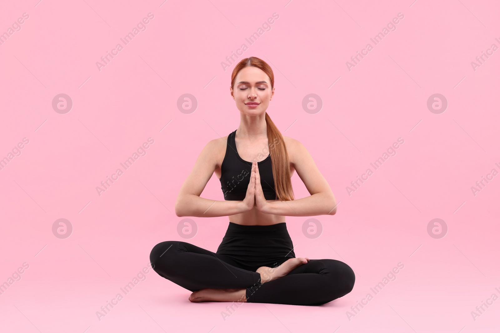 Photo of Beautiful young woman practicing yoga on pink background. Lotus pose