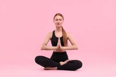 Photo of Beautiful young woman practicing yoga on pink background. Lotus pose