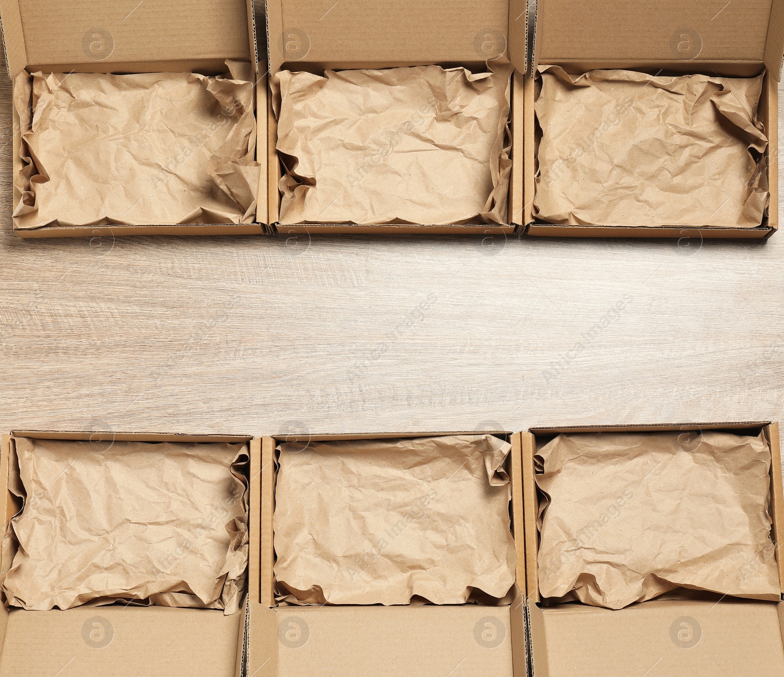 Photo of Many open cardboard boxes with crumpled paper on wooden background, flat lay. Space for text