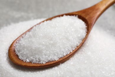 Wooden spoon and granulated sugar, closeup view