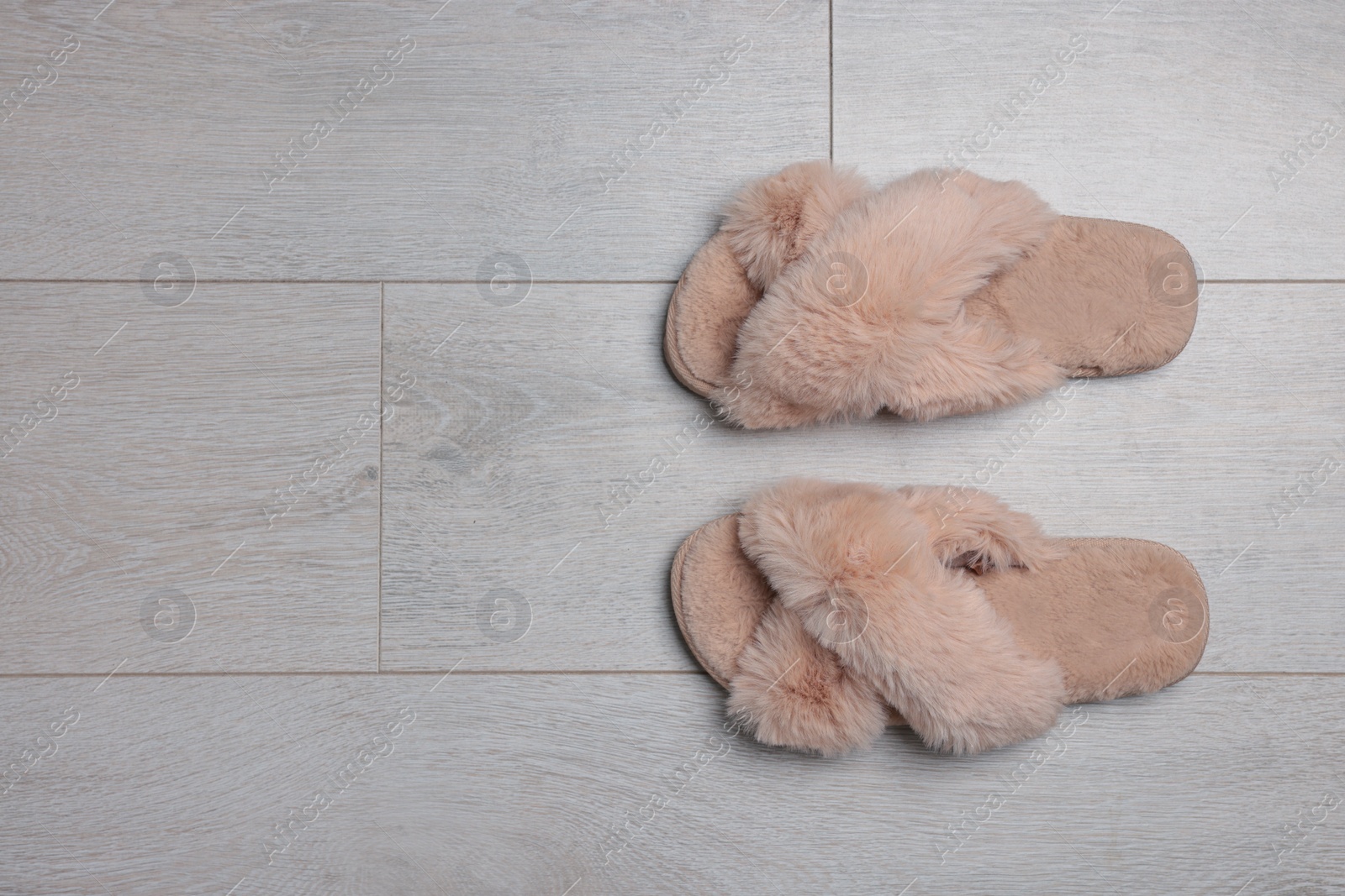 Photo of Pair of soft slippers on wooden floor, top view. Space for text