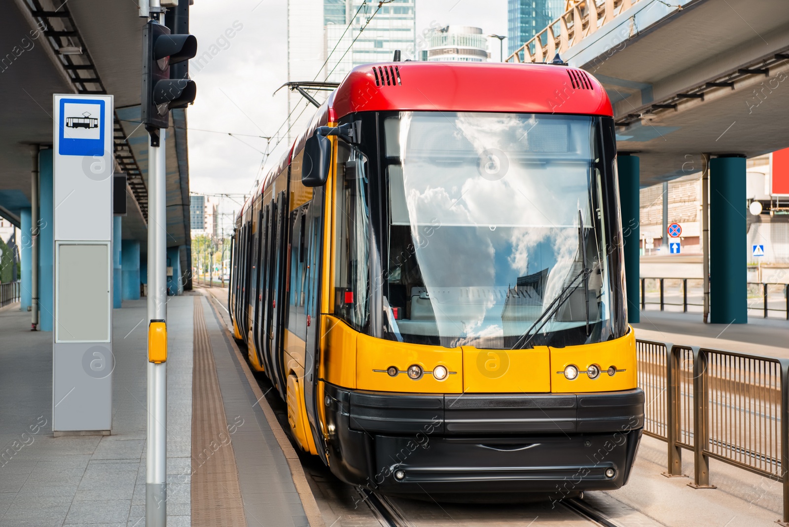 Photo of Modern streetcar near tram stop on sunny day. Public transport