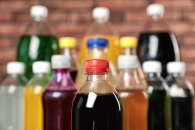 Photo of Bottles of soft drinks near brick wall, closeup