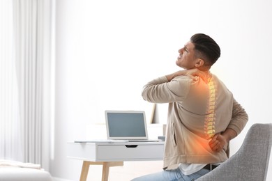 Image of Man suffering from back pain at workplace. Bad posture problem