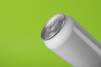Photo of White can of energy drink on light green background, closeup. Space for text